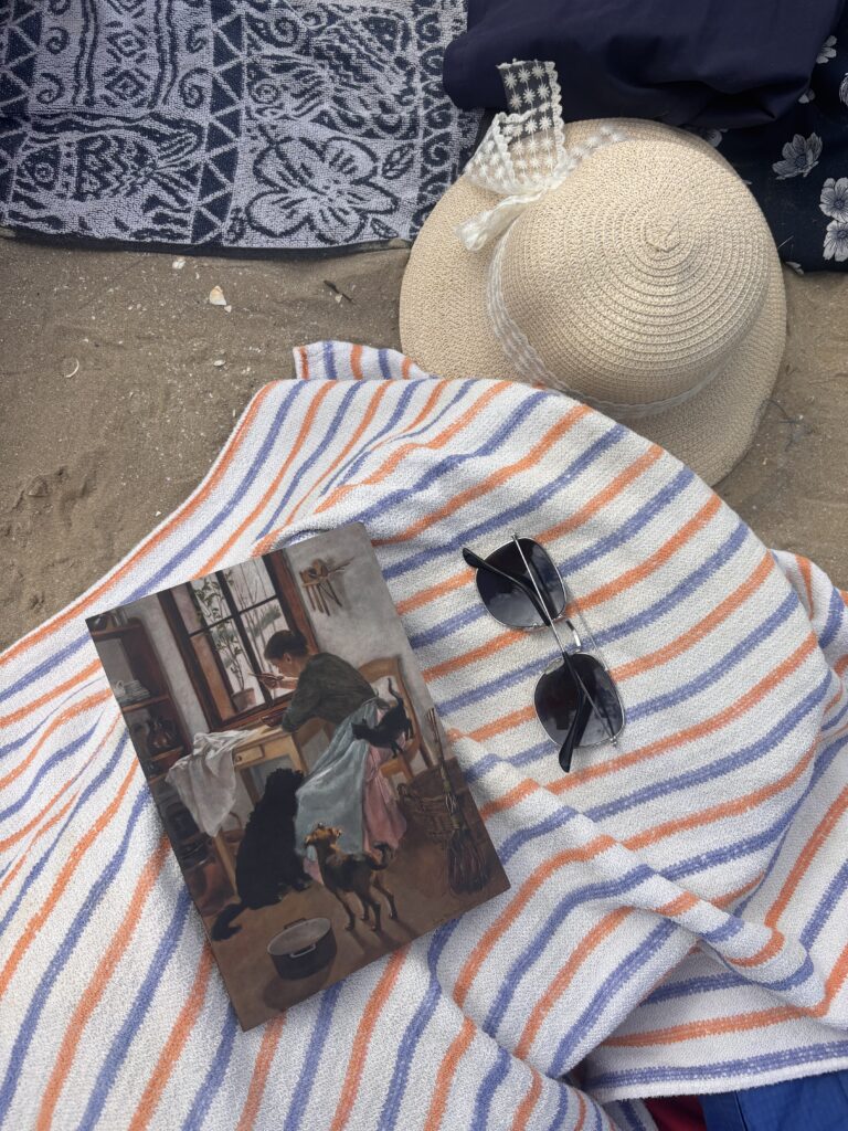 zeszyt z obrazem Leony Bierkowskiej leżący na ręczniku na plaży